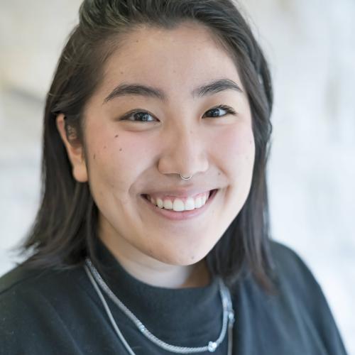 JJ smiling in front of a cream coloured wall 